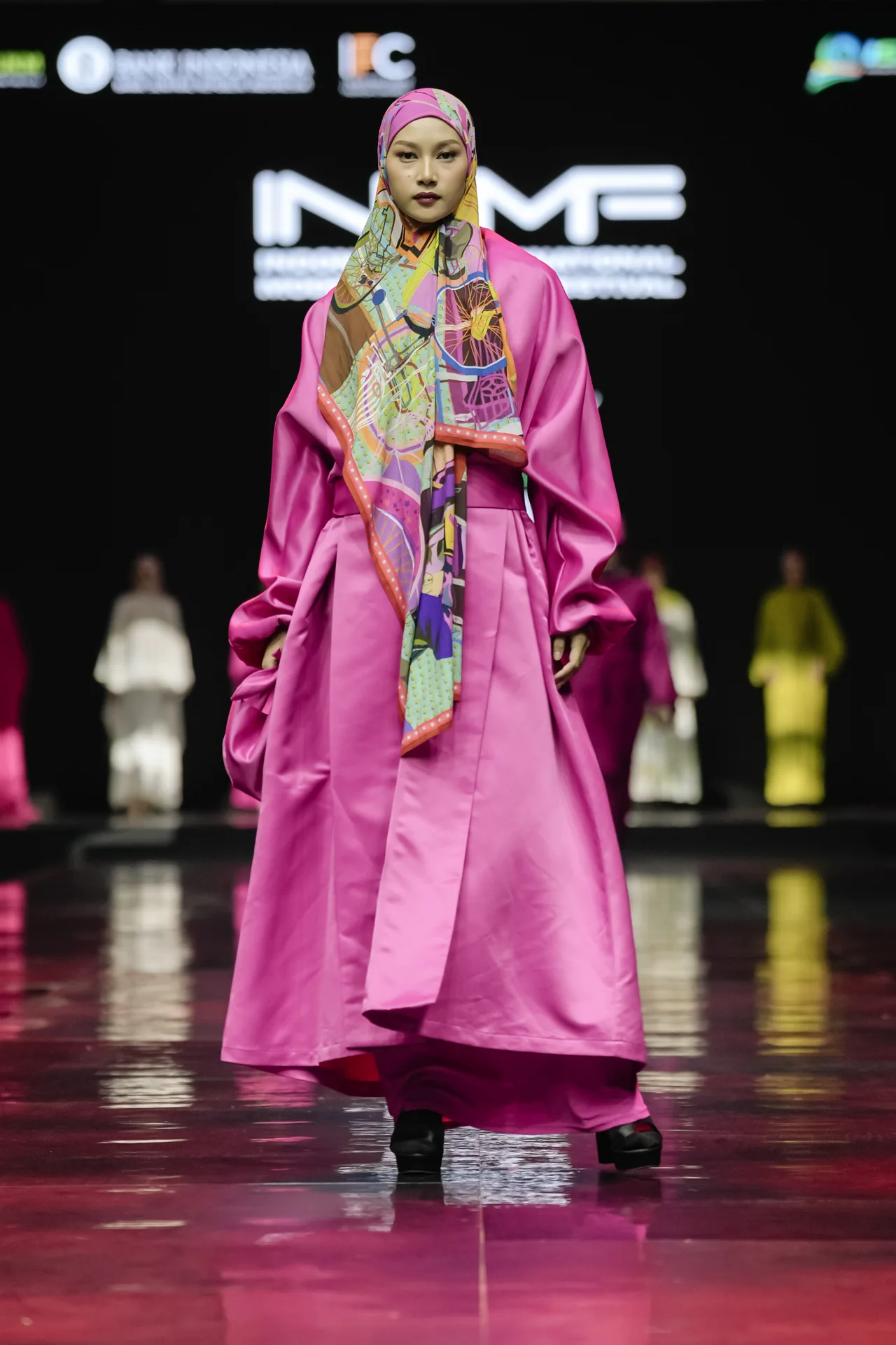 Hijab fashion model on runway wearing bright magenta satin kimono gown and colorful headscarf
