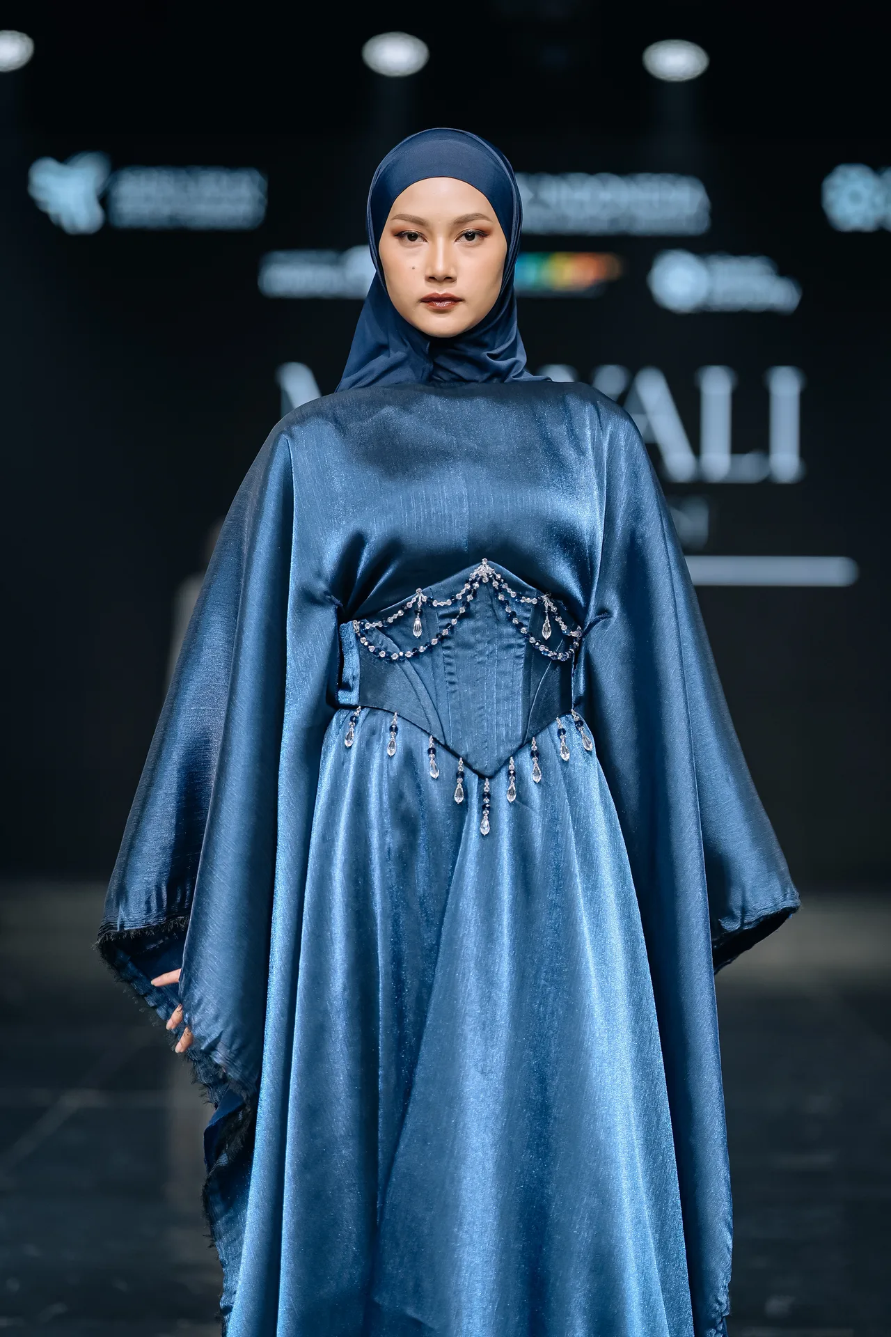 Gina on the runway in a metallic blue satin gown