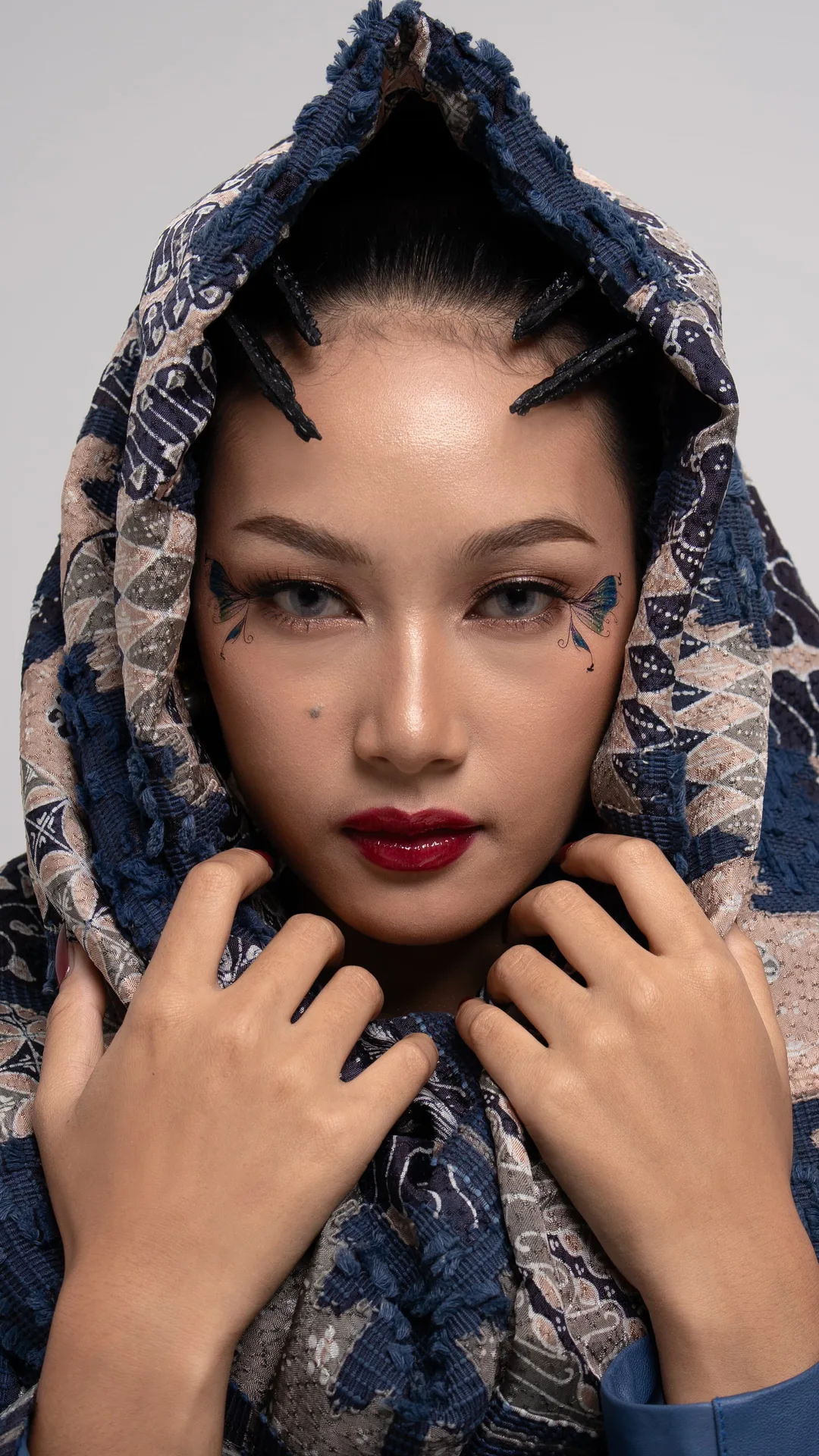 Close-up studio beauty portrait of model in traditional patterned headscarf cowl with spiked hair horns