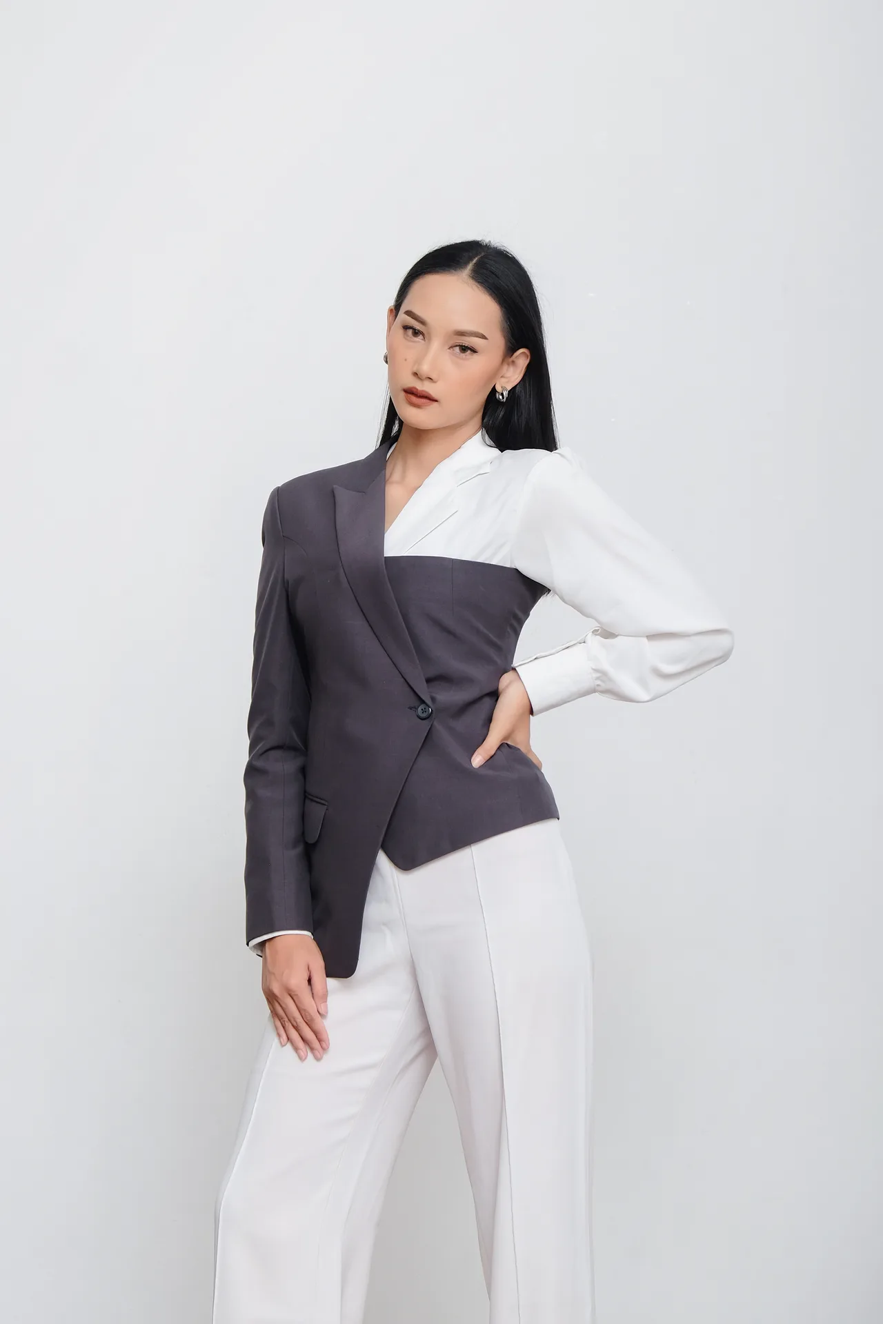 Catalog lookbook shoot of model in modern asymmetric two-tone grey and white blazer suit with white trousers